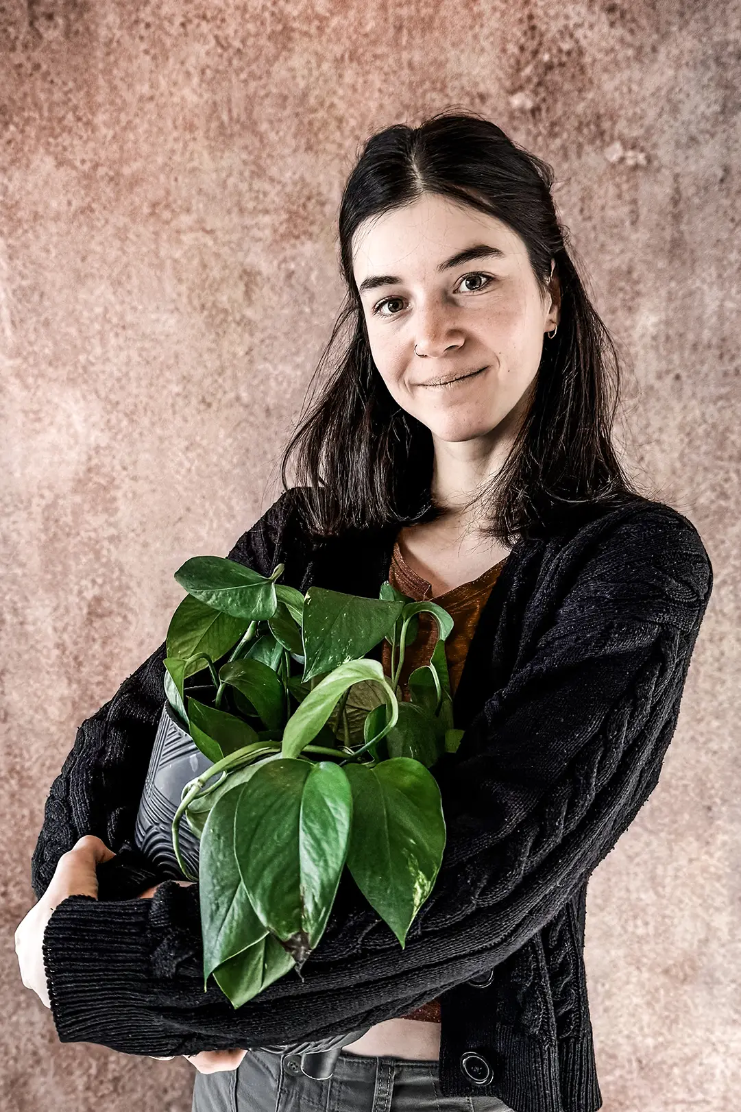 tatovering stavanger - Tattoo-lærling Regina hos Inspirit Tattoo i Stavanger, smilende med en grønn plante i armene. Lærling hos anerkjent tatoveringsstudio.